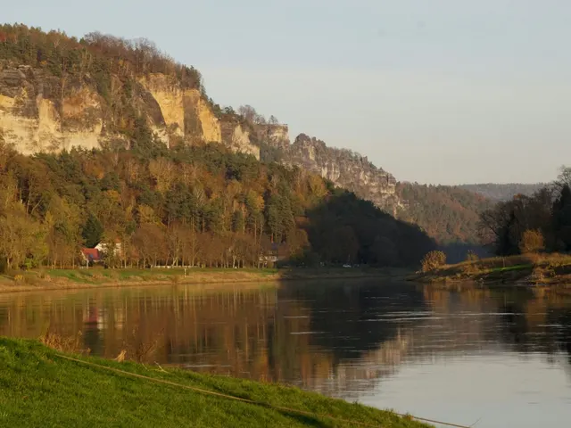 Evening light over the Elbe river below a sandstone cliff in the Elbsandsteingebirge near Stadt Wehlen, with autumn-colo jigsaw puzzle
