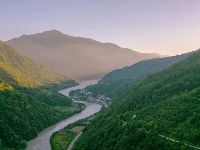 A winding river flows through a lush green mountain valley jigsaw puzzle