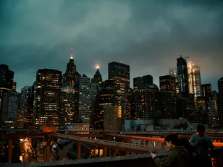 man in white shirt sitting on red metal bridge during night time jigsaw puzzle